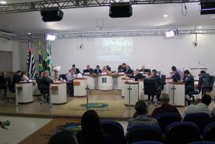 #PraCegoVer: Foto mostra visão geral do plenário com parte do público presente assistindo à sessão. No centro, os vereadores estão sentados nos seus lugares.