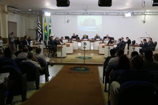 #PraCegoVer: Foto mostra o plenário da Câmara. No centro estão os vereadores sentados em seus lugares, e nas laterais parte do público presente.