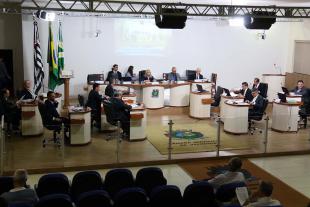 #PraCegoVer: Foto mostra o plenário da Câmara visto de cima, com os vereadores sentados em seus lugares e parte do público acompanhando a sessão.