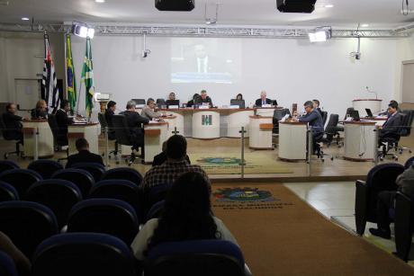 #PraCegoVer: Foto do plenário da Câmara visto de cima mostra os vereadores em seus assentos e parte do público presente.